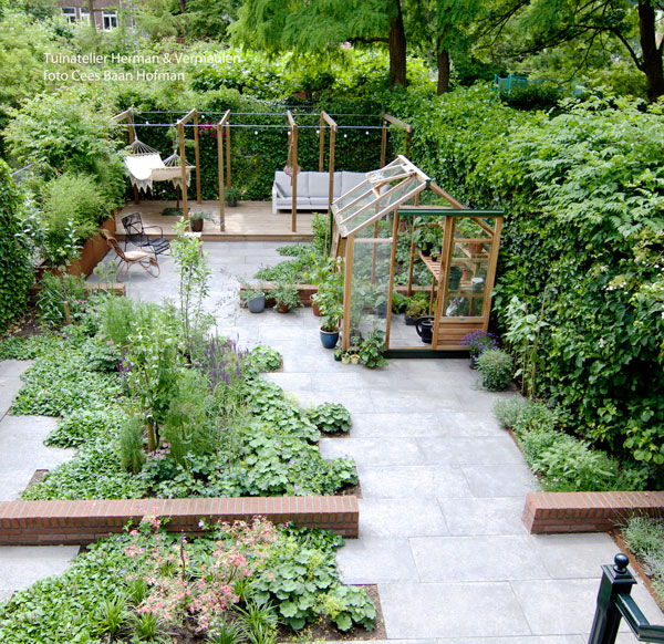 moderne groene tuin met verspringende tegels en een houten kas en pergola