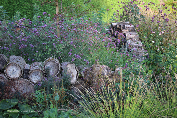 een bostuin of woodland garden met een muurtje van stammetjes